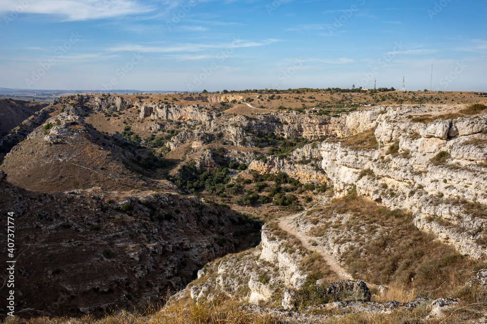 View of Gravina river canyon and park of the Rupestrian Churches of Matera with houses in caves di Murgia Timone near ancient town Matera (Sassi), , Basilicata, Italy View of Gravina river canyon and park of the Rupestrian Churches of Matera with houses in caves di Murgia Timone near ancient town Matera (Sassi), , Basilicata, Italy
