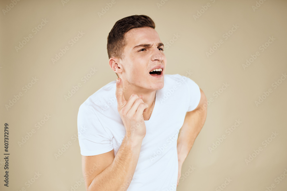 Emotional man facial expression gesture with hands white t-shirt beige background Emotional man facial expression gesture with hands white t-shirt beige background