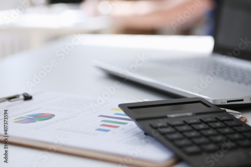 Black calculator and financial statistics on clipboard pad at office table closeup. Internal Revenue Service inspector sum check, irs investigation, earnings, savings, loan and credit concept