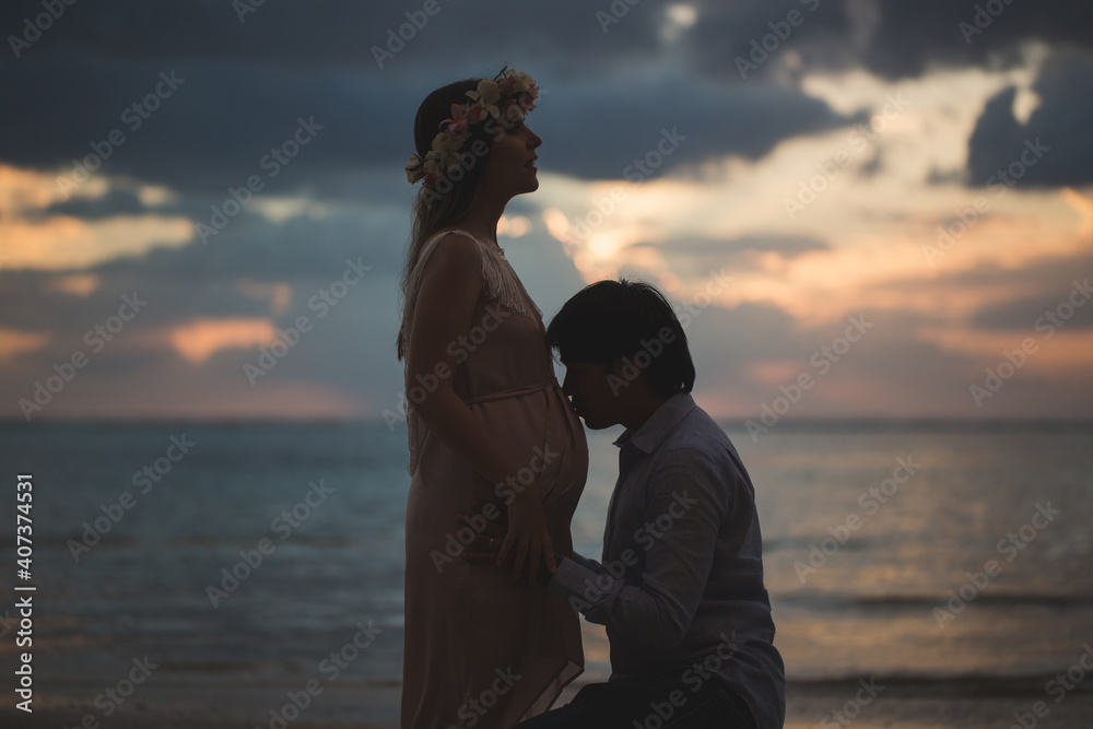 Beautiful pregnant girl and man at sunset