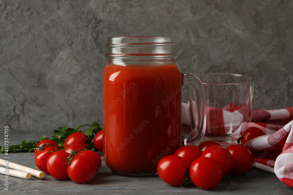 Jar of tomato juice, tomatoes and kitchen towel on wooden background Jar of tomato juice, tomatoes and kitchen towel on wooden background