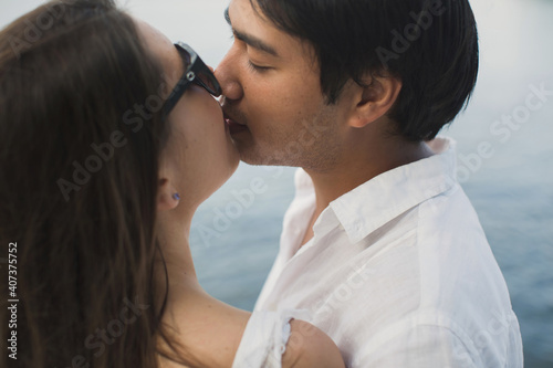 Young couple is traveling on a yacht in the Indian ocean. Man and a woman stand on the edge of the boat and kiss