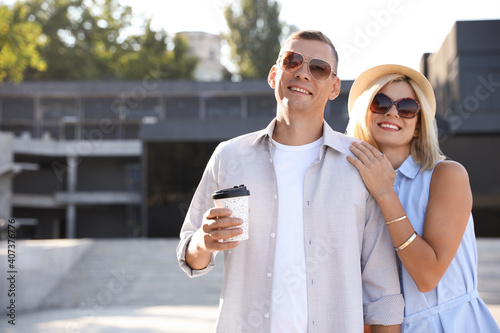 Happy couple with drink walking along city street on summer day © New Africa