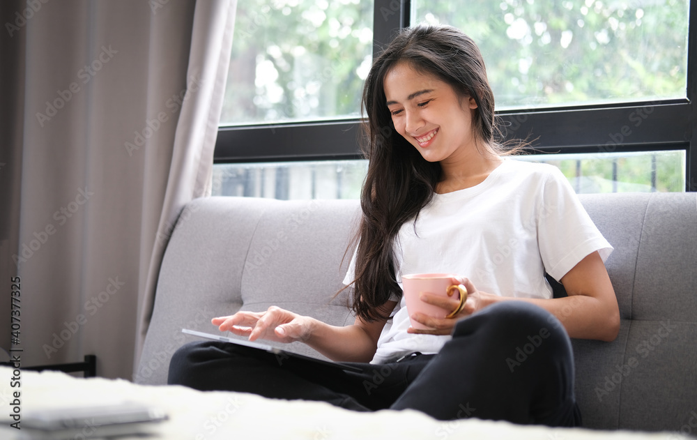 Smiling young woman sitting on comfortable sofa and using digital tablet. Smiling young woman sitting on comfortable sofa and using digital tablet.