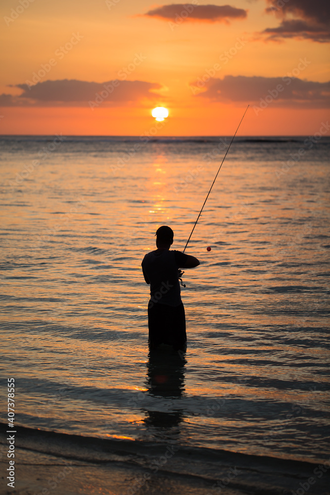 A man fishing in the Indian ocean with the beach at sunset A man fishing in the Indian ocean with the beach at sunset