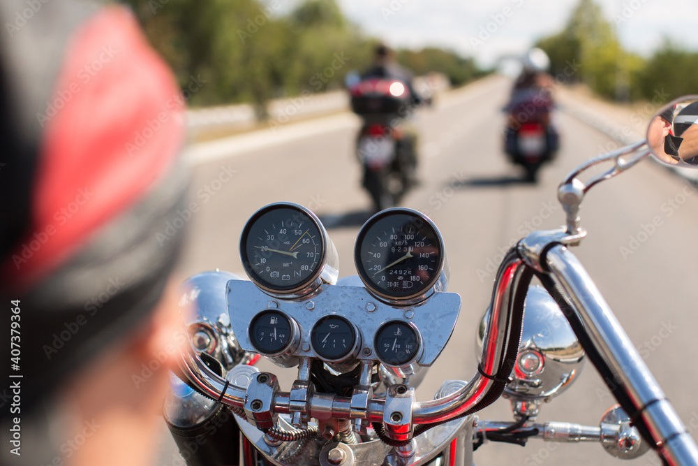 Biker riding motorcycle on road in morning sunny day. Shot from behind Biker riding motorcycle on road in morning sunny day. Shot from behind