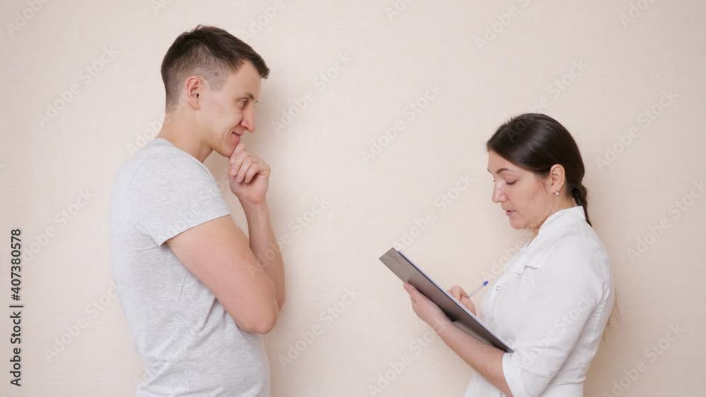 Female doctor talking to a male patient and fills out a document, taking anamnesis. Female doctor talking to a male patient and fills out a document, taking anamnesis.