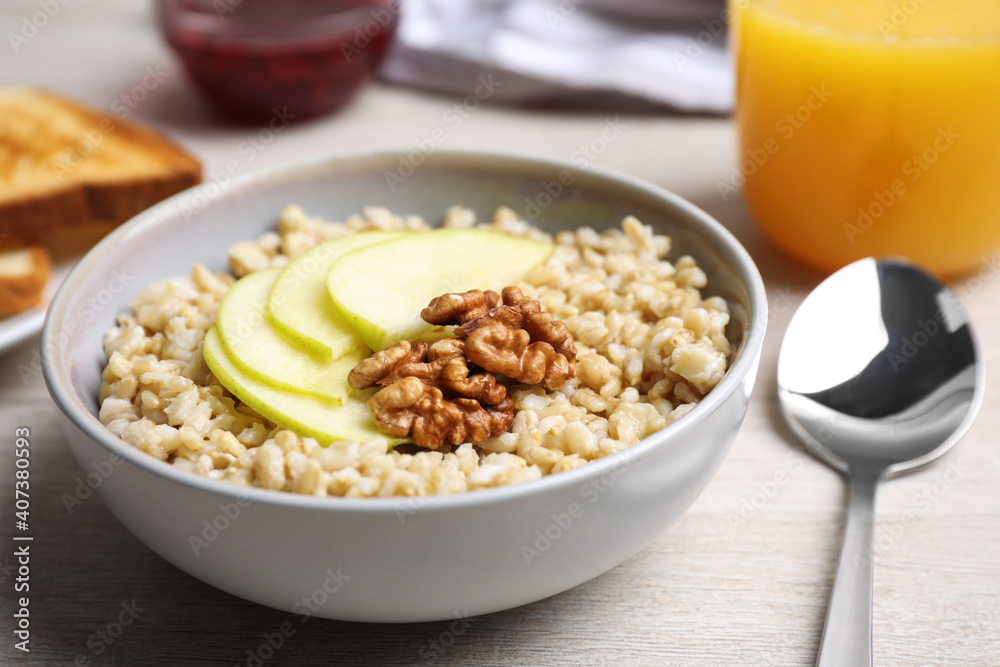 Tasty oatmeal porridge with walnuts and apple slices on white wooden table, closeup Tasty oatmeal porridge with walnuts and apple slices on white wooden table, closeup