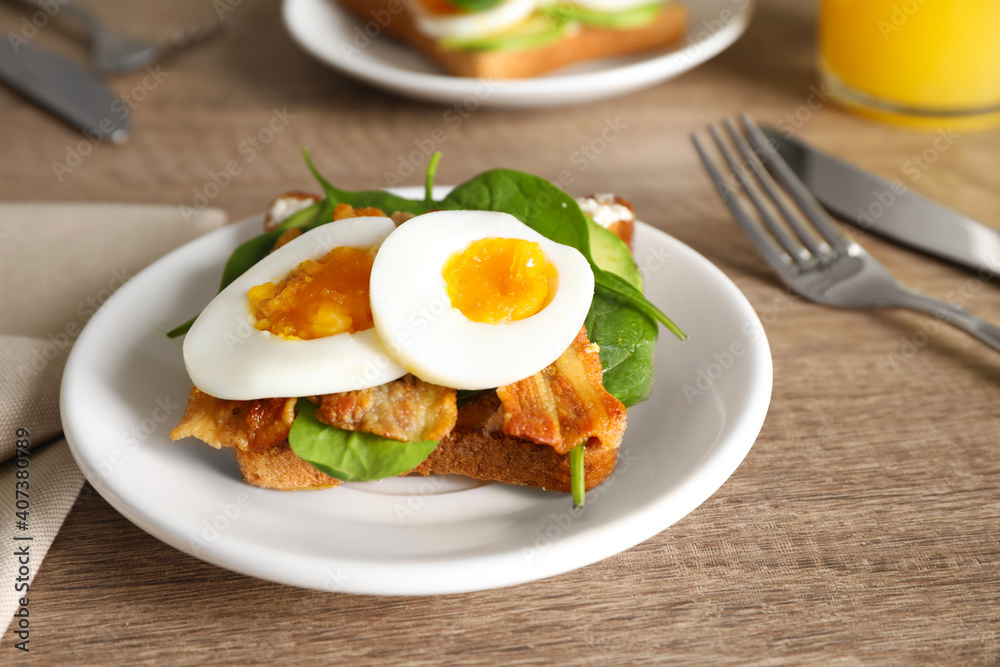 Sandwich with egg, bacon and spinach served on wooden table, closeup