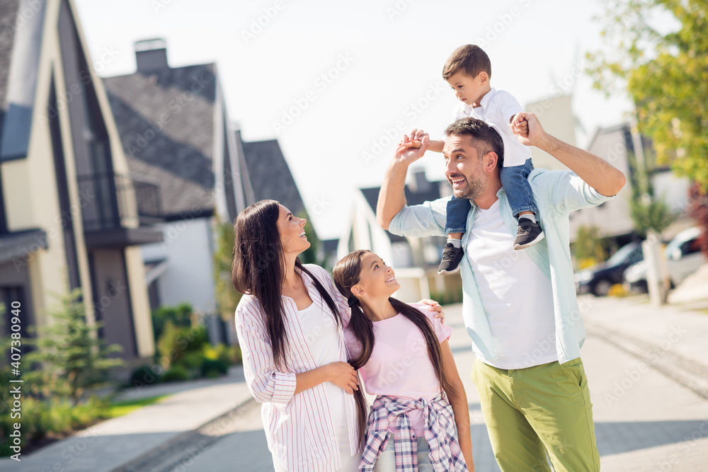 Photo of happy smiling cheerful positive family daddy carry son on shoulders mommy daughter hug each other outside outdoors