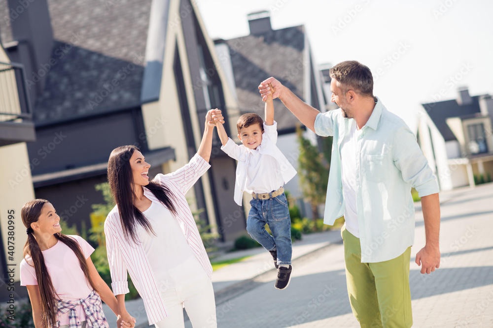 Naklejka premium Photo of pretty funky family hold boy up walk near home wear casual cloth outside
