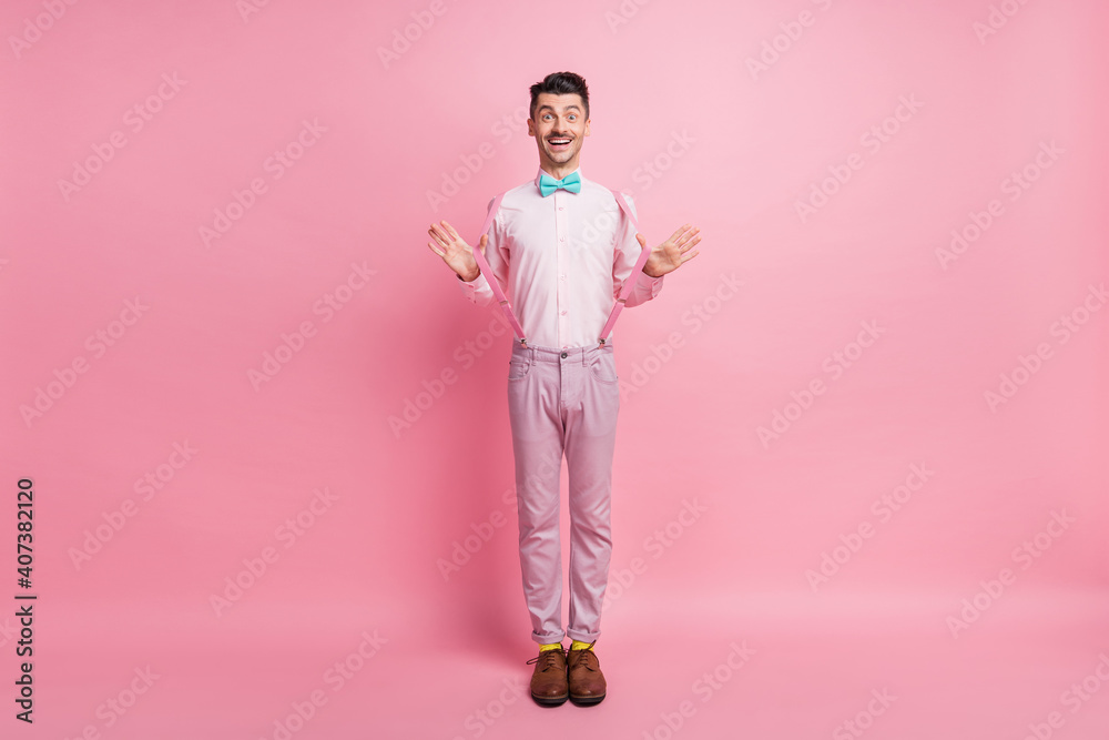 Full length photo portrait of excited man pulling suspenders isolated on pastel pink colored background Full length photo portrait of excited man pulling suspenders isolated on pastel pink colored background