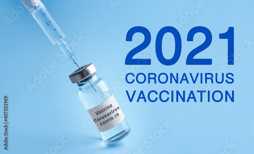 Vial with coronavirus vaccine on light blue background