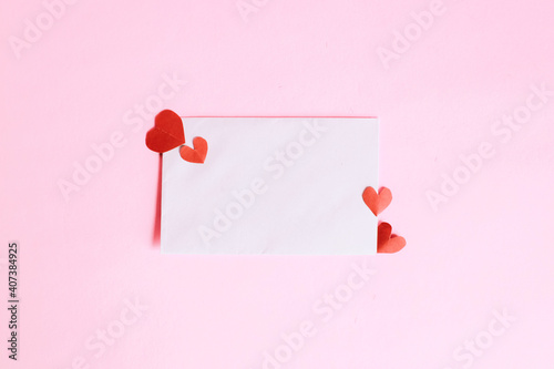 White envelope with mini heart shape on pink background
