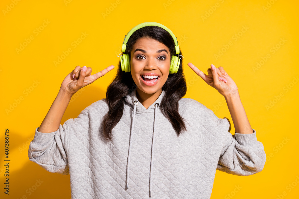 Photo of excited brown haired young afro american girl wear point headphones song isolated on yellow color background Photo of excited brown haired young afro american girl wear point headphones song isolated on yellow color background