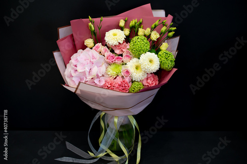 A bouquet of fresh flowers in decorative packaging. Photo on a dark background. Congratulatory bouquet.
