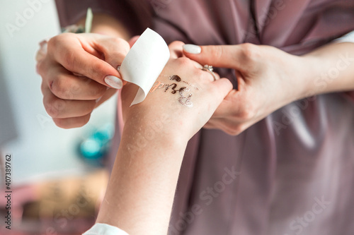 The process of sticking a temporary tattoo on the arm of the bride in the style of a bachelorette party.