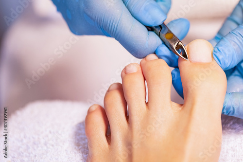 Close up of professional painting french pedicure nails on foot. Specialist in beauty salon making french pedicure for female client. Relaxing at beauty salon, caring about nails. 