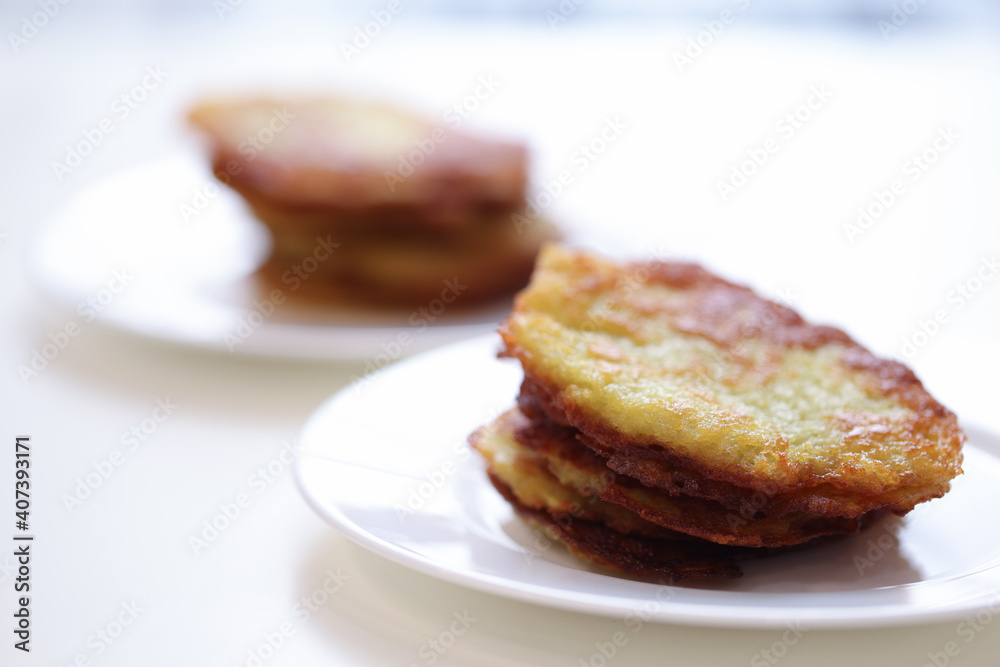 Potato latkes lying on white plate in cafe closeup