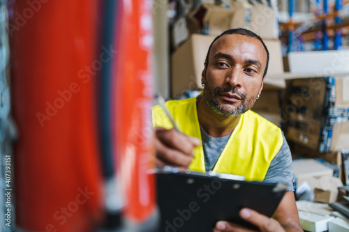 handsome african american worker checking a fire extinguisher in a warehouse