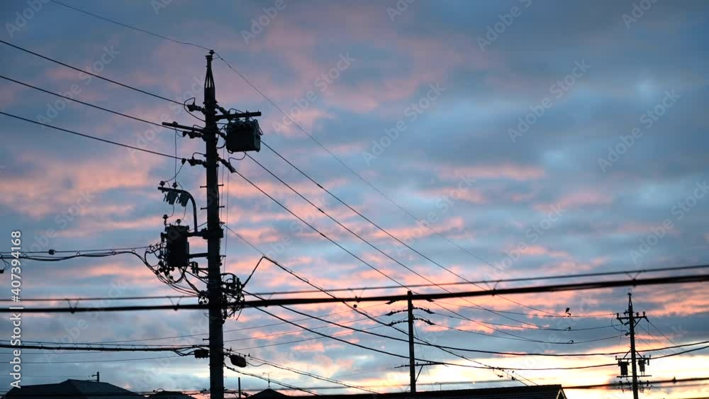 Moving clouds on an evening vanilla sky. Utility poles and electrical wires in a foreground. Stationary footage taken with Nikon z6.
