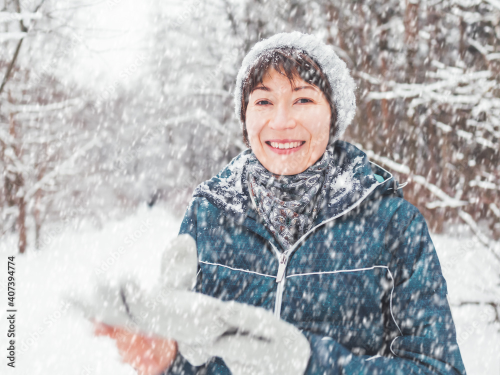 Smiling woman with gloves and knitted hat. Fun in snowy winter forest. Woman laughs as she walks through wood. Sincere emotions. Smiling woman with gloves and knitted hat. Fun in snowy winter forest. Woman laughs as she walks through wood. Sincere emotions.