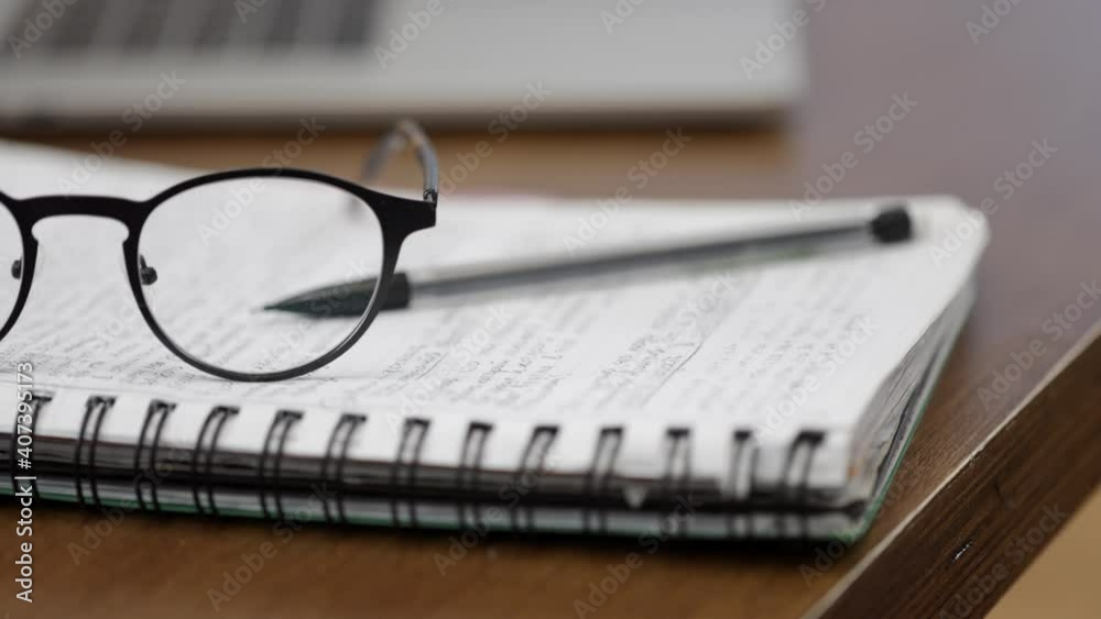 Close up glasses, a laptop and a notebook with a pen are on the desktop. The concept of business, work, study.