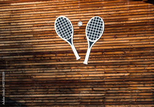 Tennis rackets and tennis ball sign on wooden background