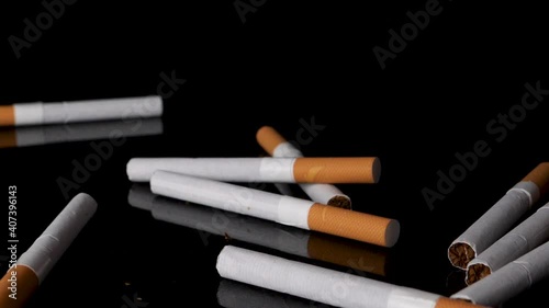 Pile of cigarettes dropping and bouncing on black background in slow motion.