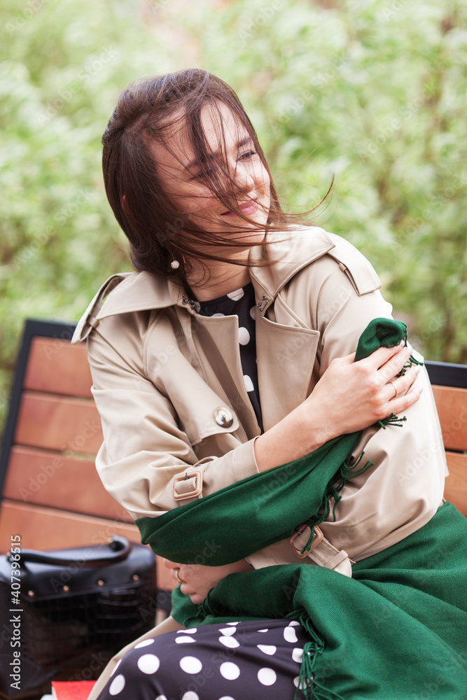 Smiling beautiful girl siting in a city park on a bench . Wind developing long hair of happy young woman. Smiling beautiful girl siting in a city park on a bench . Wind developing long hair of happy young woman.