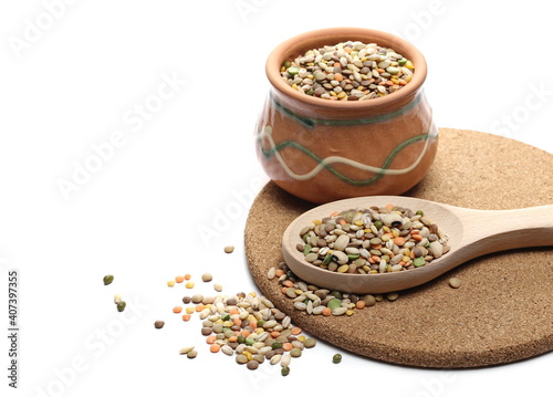 Photos Mixed legumes, cereals on round cork mat with clay bowl andwooden spoon, peeled