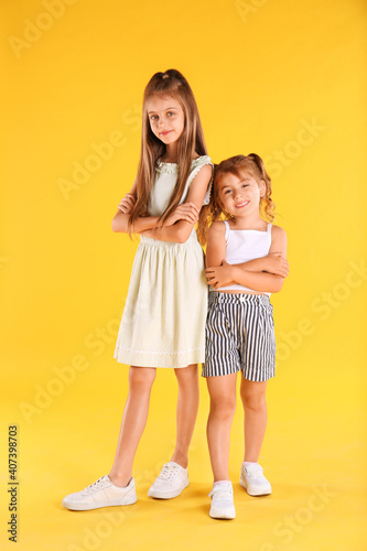 Full length portrait of cute girls on yellow background
