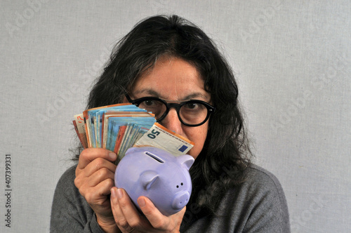 Femme radine tenant une tirelire et de billets de banque en main photo