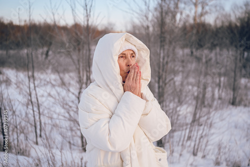 Happy elderly senior mature woman in white warm outwear playing with snow in sunny winter outdoors. Retired healthy people holiday vacation winter activities, active lifestyle concept.