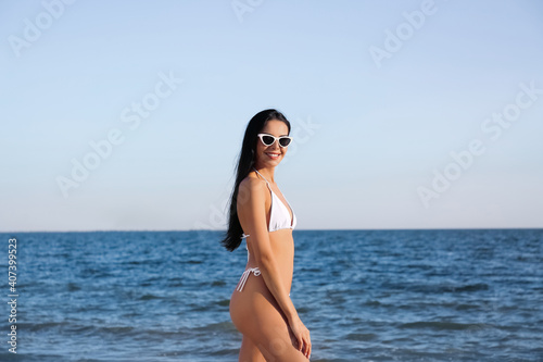 Beautiful young woman in white stylish bikini on beach
