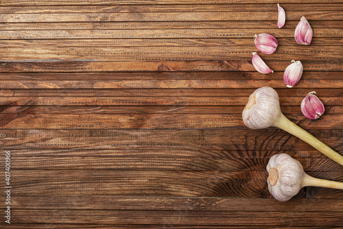 two heads of garlic and its cloves lie on the right side of the kitchen table