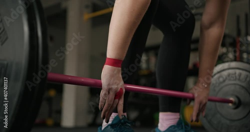 Crop sportswoman preparing to lift barbell, hands closeup