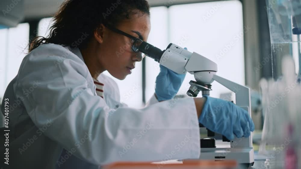 Medical Science Laboratory: Beautiful Black Scientist Looking Under Microscope Does Analysis of Test Sample. Young Biotechnology Specialist, Using Advanced Equipment. Side View Zoom In Portrait