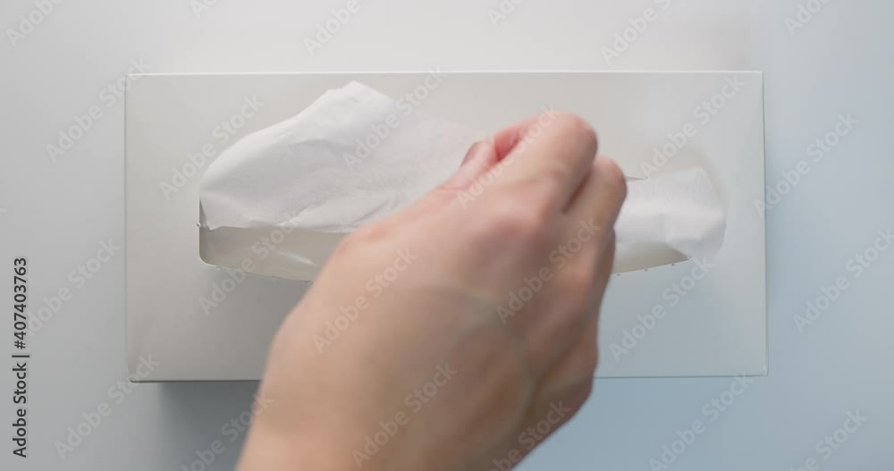 Man hand pull out a piece of tissue from white tissue paper box two time in slow motion from vertical view.