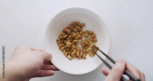 Man hand mixing Natto (fermented Japanese soybeans) in white bowl on white table. Natto is a traditional Japanese food made from soybeans that have been fermented with Bacillus subtilis var. natto photo