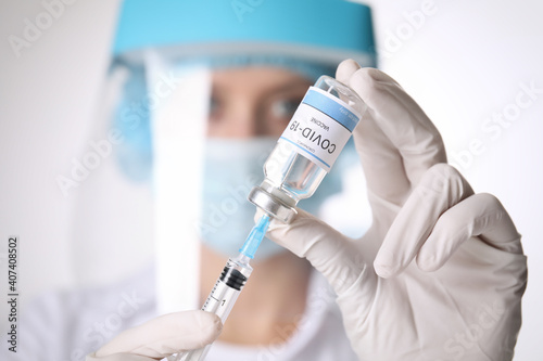 Doctor filling syringe with vaccine against Covid-19 on white background  closeup