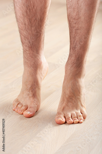 man doing flatfoot correction gymnastic exercise standing on toes at home