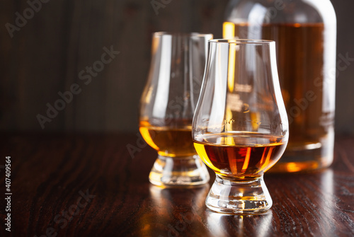 Bottle and glass of whisky spirit brandy on dark brown background