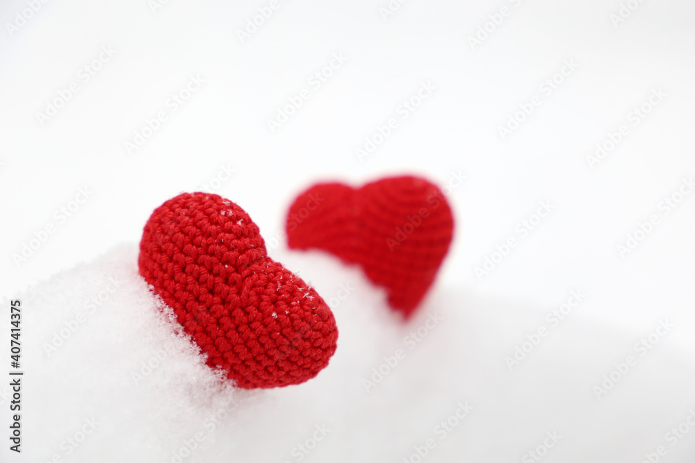 Valentine hearts in the snow. Two red knitted hearts in winter, symbol of romantic love, background for holiday