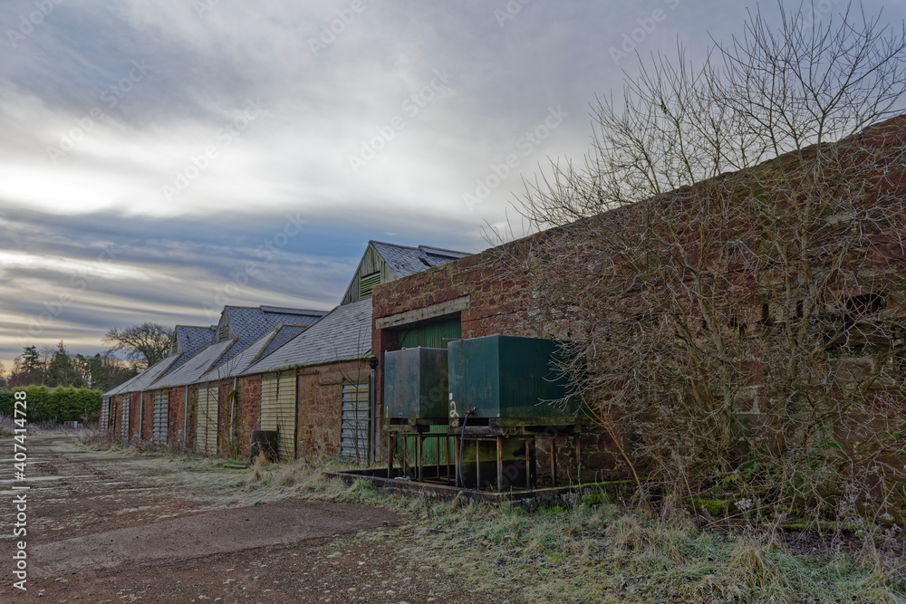 A ruined Farm Building or Agricultural Store with two empty Fuel Tanks beside one of the stone walls next to a metal sliding door. A ruined Farm Building or Agricultural Store with two empty Fuel Tanks beside one of the stone walls next to a metal sliding door.