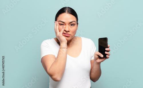 hispanic woman feeling bored, frustrated and sleepy after a tiresome, dull and tedious task, holding face with hand