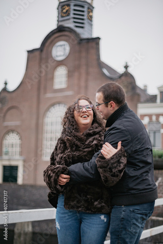 Two people in love walking around the old town in The Netherlands, hugging each other and kissing. A young woman and a man, a couple.