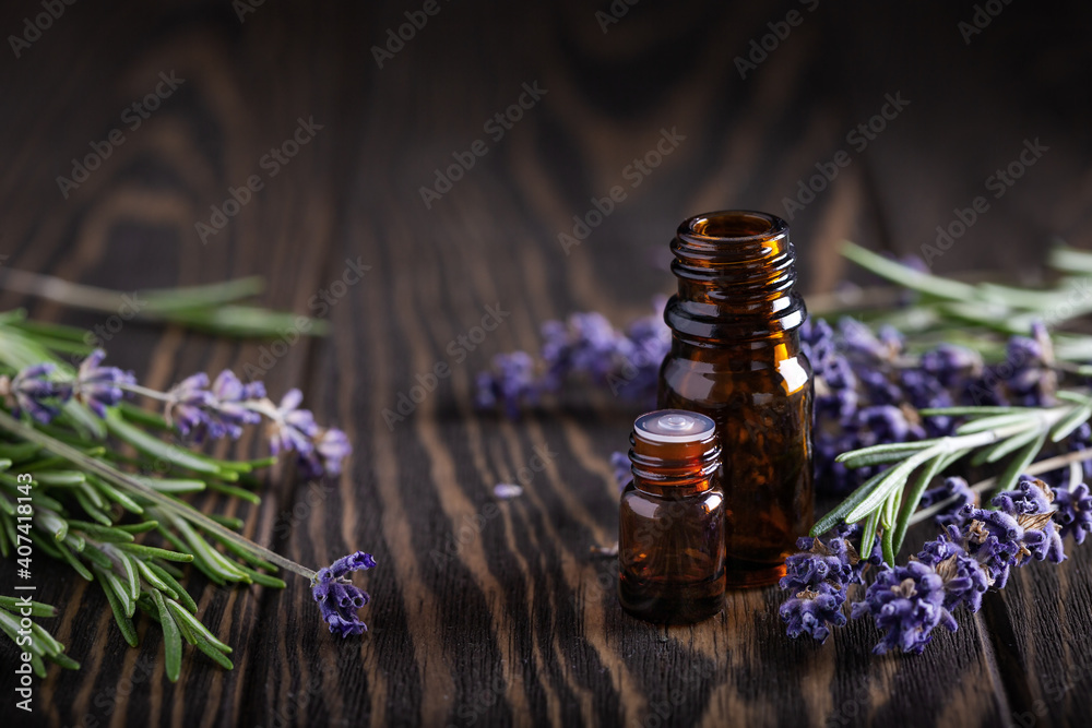 Rosemary and lavender essential oils in dark glass bottles on wood Rosemary and lavender essential oils in dark glass bottles on wood