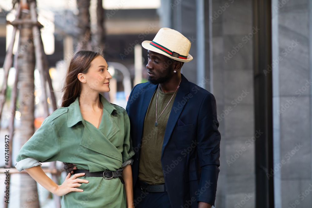 Portrait of beautiful woman and handsome afro man in dark blue color suit and hat hipster and vintage style walking and dance on street