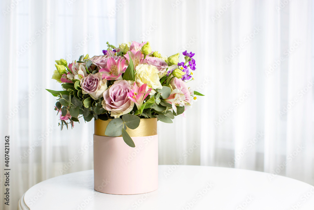Beautiful bouquet of flowers in pink round box on a white table. Gift for holiday, birthday, Wedding, Mother's Day, Valentine's day, Women's Day. Floral arrangement in a hat box. Beautiful bouquet of flowers in pink round box on a white table. Gift for holiday, birthday, Wedding, Mother's Day, Valentine's day, Women's Day. Floral arrangement in a hat box.